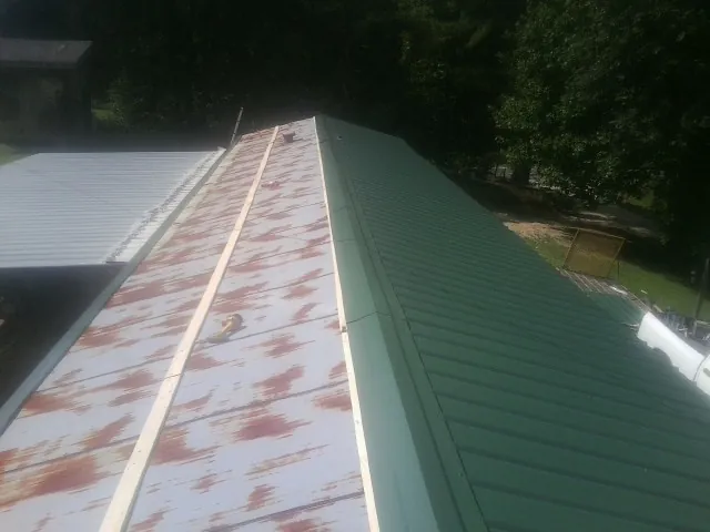 Old rusted panels beside newly installed green metal roofing — Wind Damage Roof Repair by Roofing Brothers in Beloit
